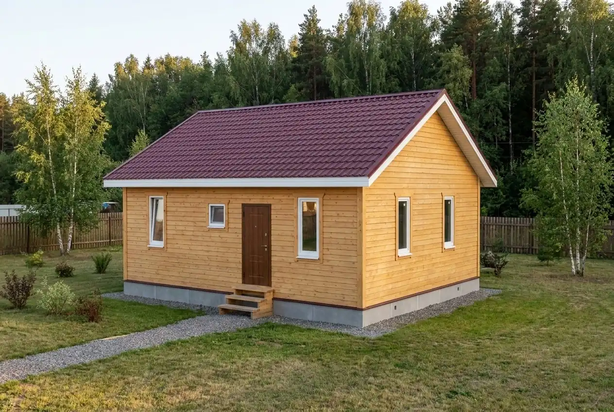 Каркасный дом 8×9 м в один этаж, три спальни, с двускатной кровлей из металлочерепицы, вид спереди-справа: на торце 2 окна; на длинной стене 3 окна и входная дверь со ступенями.